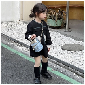 Photo de rue d'une fille en robe noire avec un sac seau bleu matelassé en cœur