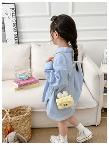 Girl's quilted shoulder bag with white bow and chain strap in a cozy interior setting