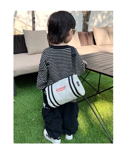 Close-up of kids' trendy bucket crossbody bag with black stripes and red logo detail