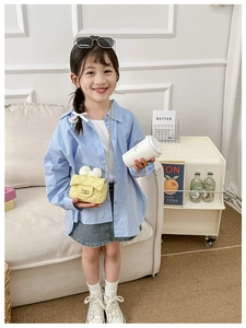 Close-up of girls' yellow quilted chain bag with large white bow detail on child model