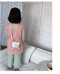 Rear view of toddler girl outfit with pink knit vest and white crossbody bow bag
