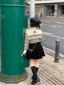 Close-up of kids black pleated skirt paired with a mini bronze chain crossbody bag