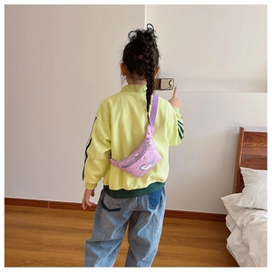Rückansicht eines Kindes mit lila Einhorn-Brusttasche in einem hellen Wohnzimmer