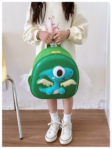 Detail shot of a green dinosaur backpack with 3D cartoon scales on a child model