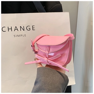 Detail view of pink patent leather mini bag with bow decoration and adjustable strap