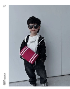 Detail of pink cylindrical kid's crossbody bag with sporty stripes and durable fabric
