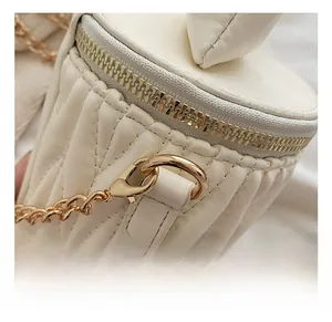 Détail d'un sac seau blanc matelassé avec bandoulière chaîne dorée et mousqueton
