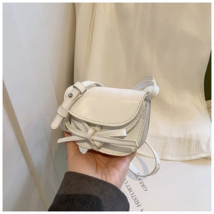 Close-up of a mini white PU leather handbag with a bow and adjustable shoulder strap