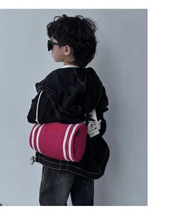 Close-up of fuchsia cylinder crossbody bag featuring white stripes and red embroidery