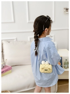 Rear view of a girl wearing a yellow quilted mini crossbody bag with a white bow