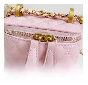 Détail du sac seau rose matelassé montrant les doubles fermetures éclair dorées et chaîne