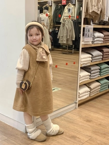 Detail view of child model wearing a stylish brown mini round bag with bronze chain strap