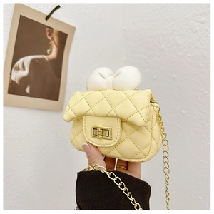 Detail of yellow quilted mini bag with white bow and golden chain strap for girls
