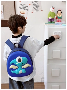 Detail of child wearing a dark blue 3D dinosaur backpack with breathable mesh straps