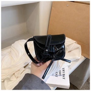 Detail of mini black patent leather bag with bow knot and glossy mirror finish