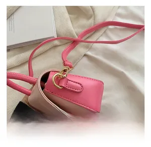 Detail of pink child's handbag showing the golden metal hook and leather strap connection