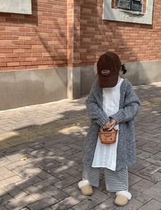 Detail of a brown patterned handbag and corduroy cap paired with a knit cardigan
