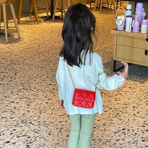 Red quilted crossbody bag for girls with gold chain strap in a stylish café setting