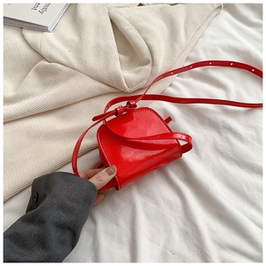 Detail of red patent leather mini bag with half-round flap and adjustable strap
