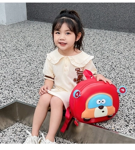 Detail of red car-shaped hardshell toddler backpack worn by a child in outdoor setting