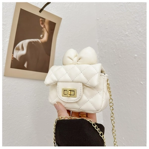 Detail of cream white quilted mini bag featuring a large bow and gold chain strap