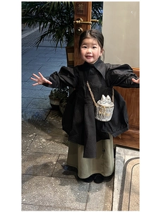 Gros plan sur robe matelassée noire et sac seau argenté à nœud pour petites filles