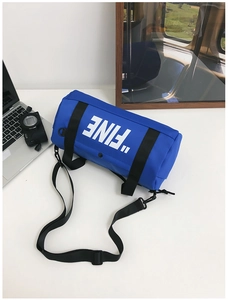 Detail view of royal blue cylindrical sports bag with white FINE letter print and strap
