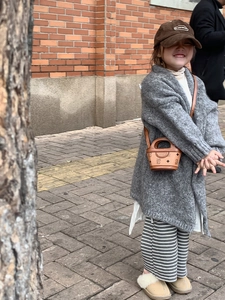 Close-up of a mini retro bear bucket bag paired with a trendy knit kids autumn outfit