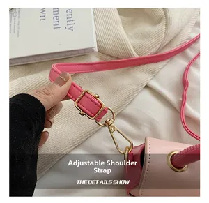 Detailed close-up of pink leather adjustable shoulder strap with gold metal buckle