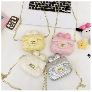 Detailed macro view of girls quilted chain bags with bows in yellow, pink, and white