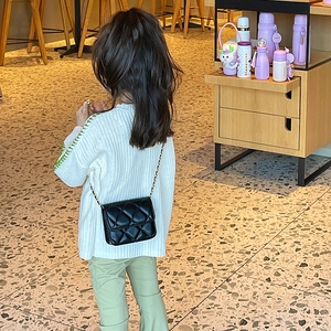 Kids quilted black crossbody bag with gold chain strap worn by child model