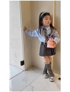 Tenue preppy fille avec chemise bleu clair, jupe plissée grise et sac rose à chaîne