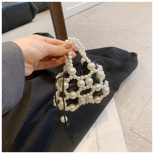 Dettaglio mini borsa a secchiello di perle con interno nero e manico di perle
