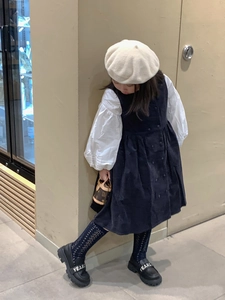 Detail of a navy double-breasted dress and white puff sleeve shirt for girls' fashion