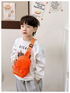 Detail der leuchtend orangen Kinder-Brusttasche mit COOL BOY-Schriftzug und Gurt