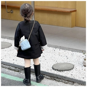 Sac seau matelassé bleu clair pour fille avec chaîne, porté sur une robe noire chic