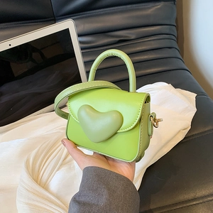 Macro detail of green mini handbag featuring a 3D heart and premium leather texture