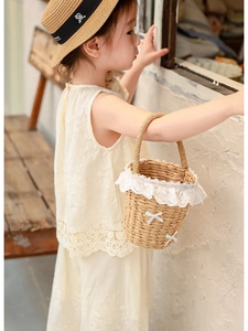 Détail du sac seau en paille fait main avec dentelle délicate et nœud blanc pour enfant
