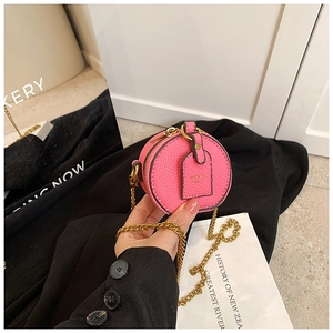 Macro view of pink pebbled leather mini round bag with gold chain and brand tag