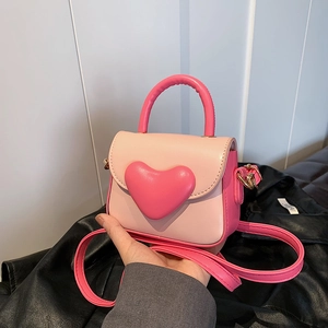 Detail of pink heart-shaped mini handbag with gold hardware and contrast paneling