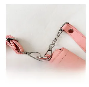 Détail d'un sac à main en cuir rose avec chaîne argentée et finitions métalliques