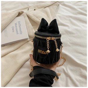 Détail du sac seau en velours noir avec nœud, broderie dorée et bandoulière chaîne