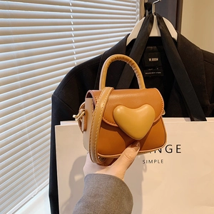 Detail of orange brown mini bag with 3D heart design and gold metal hooks for kids