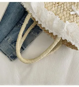 Détail du sac seau en paille avec bordure en dentelle blanche et nœud en soie élégant