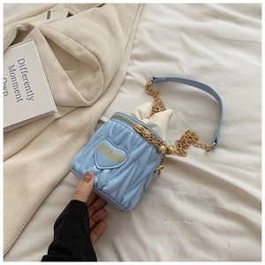 Détail du sac seau matelassé bleu clair avec motif cœur et bandoulière chaîne