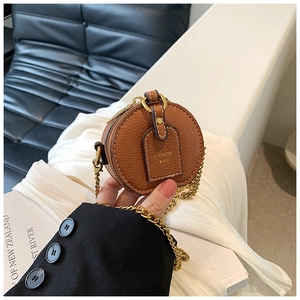 Detail of round brown faux leather mini bag featuring gold chain and FASHION BAG tag