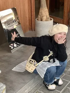 Detail of child wearing a beige mini crossbody bag with classic logo and autumn outfit