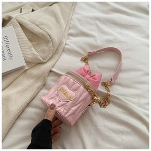 Détails d'un sac seau rose matelassé avec écusson cœur et nœud décoratif