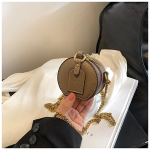 Close-up of a brown round mini bag with litchi texture leather and a gold chain strap