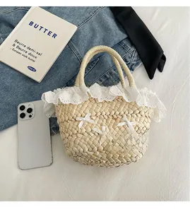 Détail d'un sac seau en paille beige avec dentelle blanche et petits nœuds en ruban
